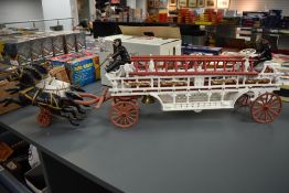 A vintage cast metal model of a Horse Drawn Fire Ladder Tender, three prancing horses, made in the