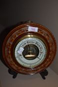 An aneroid barometer of button design with carved mahogany frame having enamel face dial