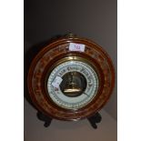 An aneroid barometer of button design with carved mahogany frame having enamel face dial