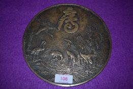 A brass cast Chinese mirror back top, bearing charcter marks and depicting cranes in flight and