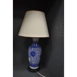 A blue and white ceramic patterned table lamp with wooden base and cream shade.