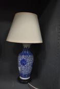 A blue and white ceramic patterned table lamp with wooden base and cream shade.