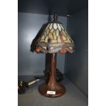 A stained glass Tiffany style desk lamp, having metal tree effect stand.