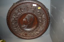 Carved wooden plaque depicting queen Victoria having leaf and floral border.