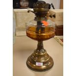 A vintage oil burning light or lamp base with glass well and brass base