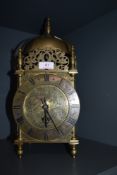 A brass cased lantern clock with chased floral face and a later electric movement