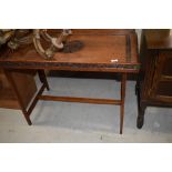 An Arts and Crafts oak tray table, having extensive foliate carving on plain frame, approx. 87 x