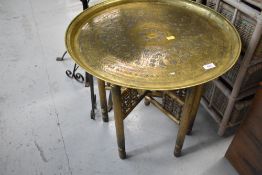 An Eastern style brass tray table, the folding frame being of spindle form, with gold spray