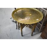 An Eastern style brass tray table, the folding frame being of spindle form, with gold spray