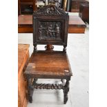 A 19th Century oak hall chair having heavily carved back, pictorial decoration depicting tavern