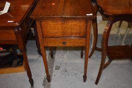 An early 20th Century oak sewing box on square tapered legs and spade feet, includes haberdashery