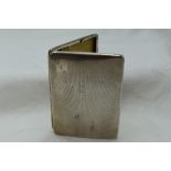 A white metal cigarette case stamped sterling silver having a slide clasp and engine turned