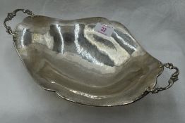 A white metal table bowl of shaped boat form having moulded handles, plannished finish and bracket