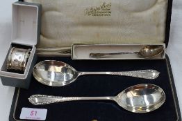 A cased pair of silver fruit serving spoons having moulded decoration to terminals and facetted