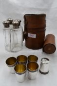 A leather cylindrical case containing four quadrant glass spirit flasks having silver screw on lids,