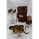 A leather cylindrical case containing four quadrant glass spirit flasks having silver screw on lids,