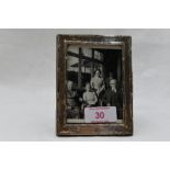 A small silver photograph frame of rectangular form having decorative border and wooden easel
