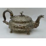 A Georgian silver teapot of squat form having a floral finial, heavily embossed floral decoration,
