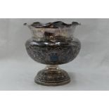 A white metal pedestal bowl having frilled edge, repousse scroll decoration to bowl and presentation