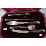 A cased Victorian seven piece carving set, missing 2 pieces having antler horn handles with silver