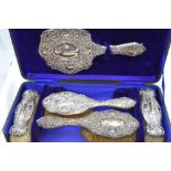 A cased Edwardian silver dressing table set (missing comb) having moulded scroll and flower