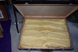A large wooden case with foam cutaways for gun stocks