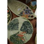 A plate in the shape of a leaf with hand painted floral design to end with embossed basket weft