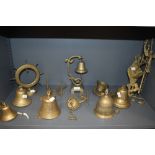 An assortment of vintage brass bells, most wall mounted with varying designs, and some wall