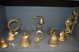 An assortment of vintage brass bells, most wall mounted with varying designs, and some wall