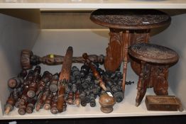 An assortment of wooden items including carved Indian styled tables and a huge array of finials or
