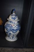 An early 20th century blue and white lidded jar of bulbous style, having band and pictorial