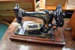 A Victorian hand crank sewing machine, by Singer, serial number 8630953 and a toffee tin of
