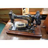 A Victorian hand crank sewing machine, by Singer, serial number 8630953 and a toffee tin of