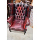 A burgundy leather button back wing armchair, little bit of heat damage to left arm hence the low