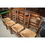 A set of four traditional oak rush seated ladder back chairs