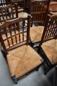 A set of four traditional oak spindle back dining chairs, having rush seats and turned frames (
