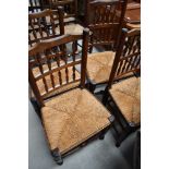 A set of four traditional oak spindle back dining chairs, having rush seats and turned frames (