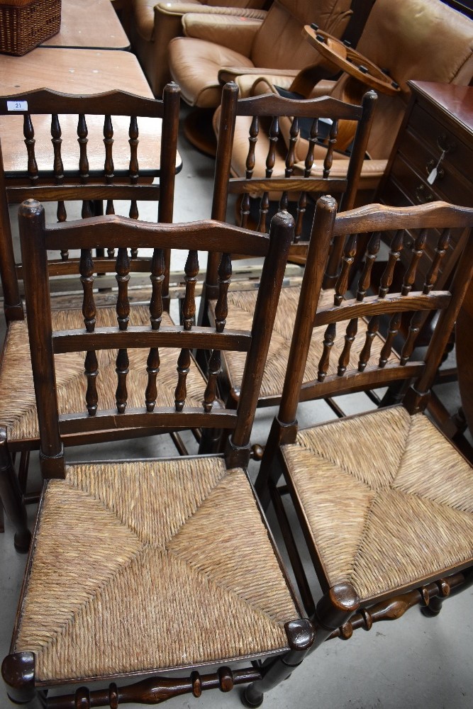 A set of four traditional oak spindle back dining chairs, having rush seats and turned frames (