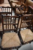 A set of four traditional oak spindle back dining chairs, having rush seats and turned frames (