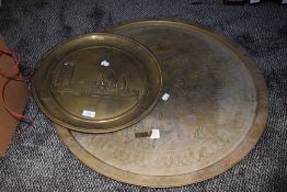 A large vintage brass Eastern styled table top and an embossed platter, possibly London scene.