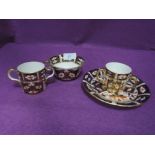 A Royal Crown Derby cup and saucer and two loving cups, one having two handles and the other