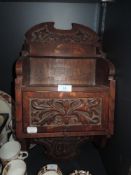 An arts and crafts style oak smokers cupboard and pipe rack having carved floral work and dated