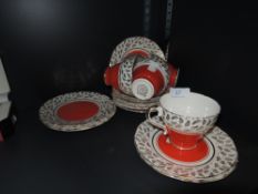 A vibrant collection of cups, saucers and side plates, having block orange centres to the plates and
