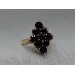 A lady's dress ring having a sapphire lozenge shaped cluster in a claw set basket mount on a 9ct