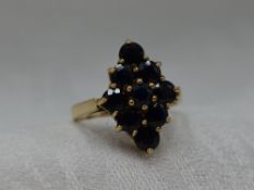 A lady's dress ring having a sapphire lozenge shaped cluster in a claw set basket mount on a 9ct