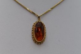 An oval Baltic amber pendant in a 9ct collared mount on 9ct gold curb chain, approx 19'