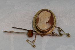 A conche shell cameo brooch depicting a maiden in profile in a 9ct gold mount and a yellow metal bar