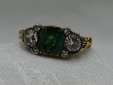 A lady's dress ring having a central emerald cut emerald, approx 1.4ct flanked by a trio of old