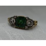 A lady's dress ring having a central emerald cut emerald, approx 1.4ct flanked by a trio of old