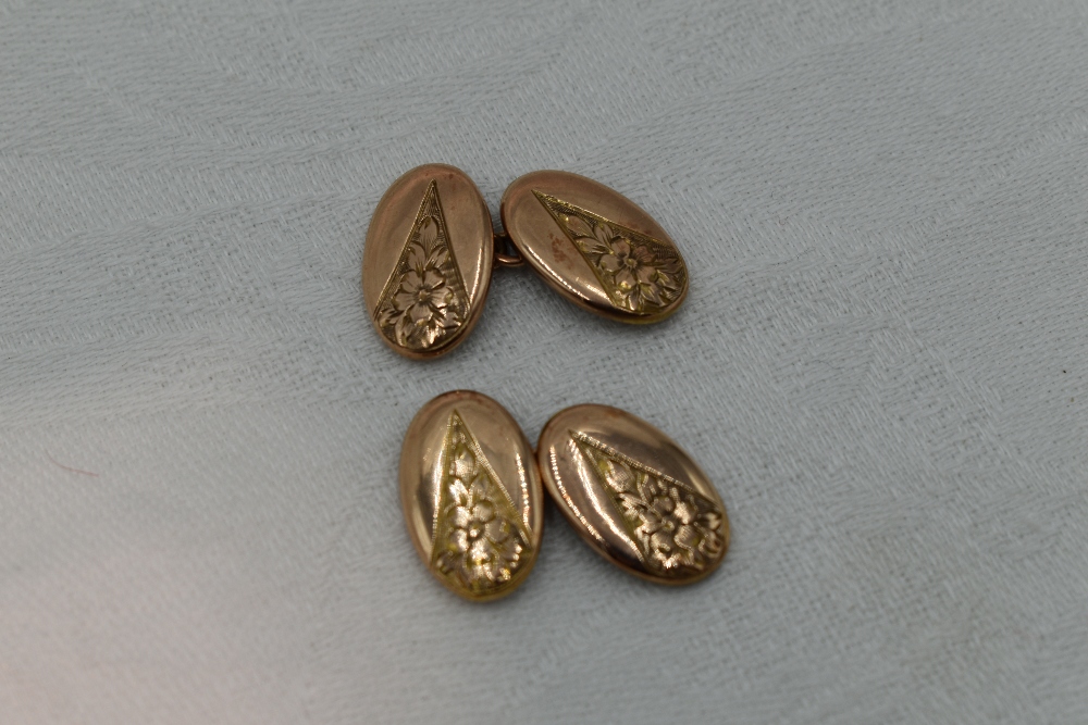 A pair of 9ct gold cufflinks of oval form having engraved floral decoration and chain connectors